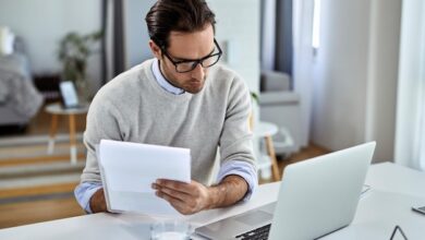 young businessman going through paperwork using laptop while working home 637285 5991 - Web Nômade Digital