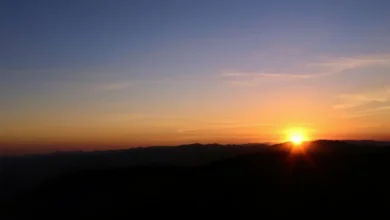 Pessoa contemplando o pôr do sol em uma montanha.