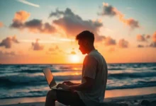Silhueta de um empreendedor nômade trabalhando em um laptop durante o pôr do sol na praia.