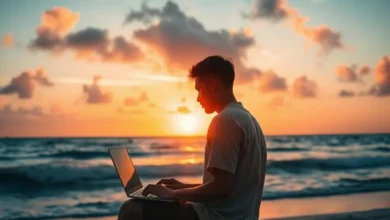 Silhueta de um empreendedor nômade trabalhando em um laptop durante o pôr do sol na praia.