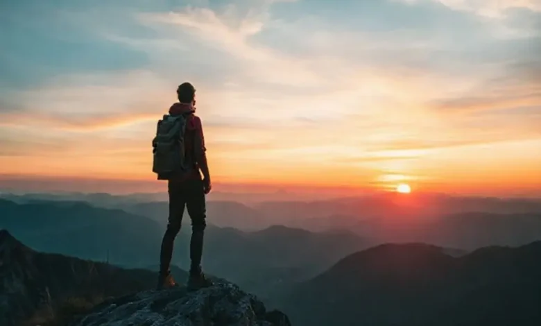Nômade digital no topo da montanha admirando um pôr do sol.