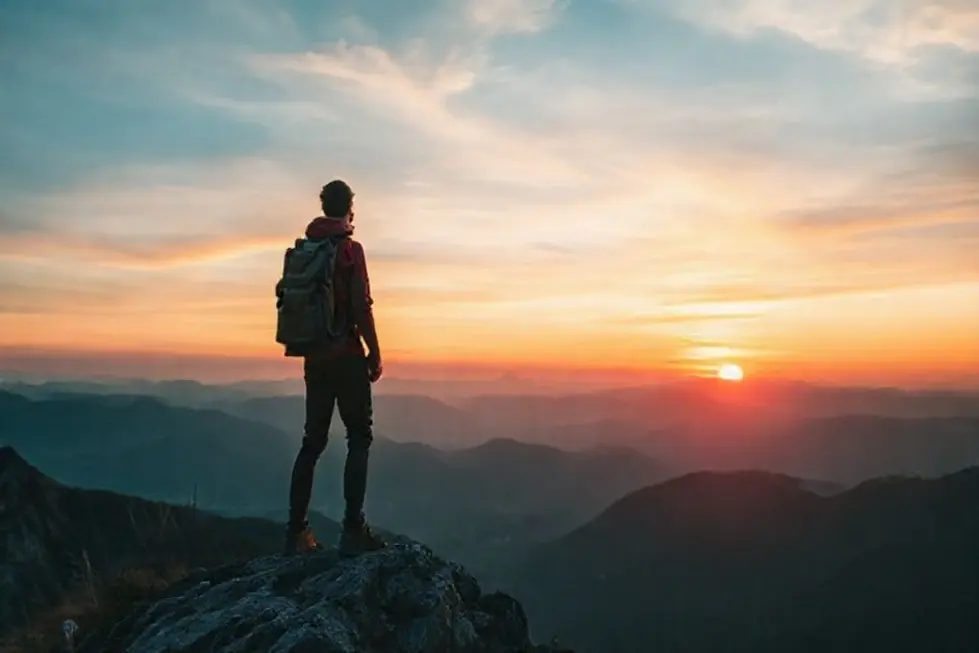 7 Passos para Atingir Crescimento Sustentável como Nômade Digital - Web Nômade Digital Nômade digital no topo da montanha admirando um pôr do sol.