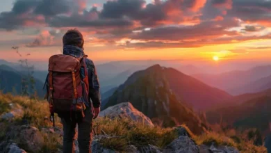 Viajante em uma trilha montanhosa encarando o pôr do sol, representando a jornada empreendedora.