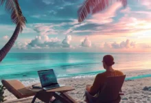 Nômade digital trabalhando em um laptop à beira-mar, representando a liberdade do empreendedorismo.