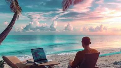 Nômade digital trabalhando em um laptop à beira-mar, representando a liberdade do empreendedorismo.