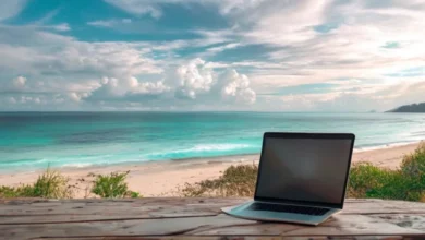 10 Mitos e Verdades sobre Empreender que Todo Nômade Digital Deve Conhecer - Web Nômade Digital Laptop aberto em uma mesa de madeira, olhando para uma praia, simbolizando a liberdade do empreendedorismo digital.