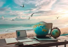 Mesa em uma praia com laptop e anotações, simbolizando liberdade financeira para nômades digitais.