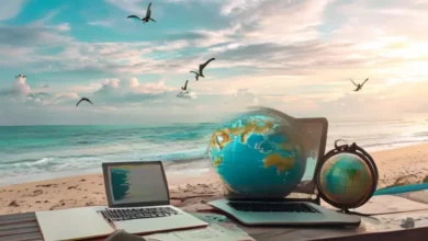 Mesa em uma praia com laptop e anotações, simbolizando liberdade financeira para nômades digitais.