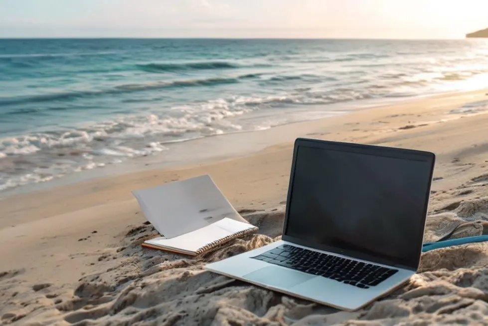 12 Estratégias para Organizar Sua Agenda e Atrair Mais Clientes Como Nômade Digital - Web Nômade Digital Cenário praiano com laptop e bloco de notas, representando nômades digitais.