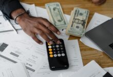 Overhead view of financial documents with calculator, cash, and laptop for financial planning.