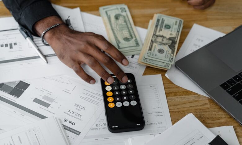 Overhead view of financial documents with calculator, cash, and laptop for financial planning.