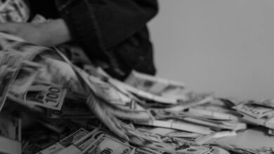 A blur of hands moving through a pile of US dollar bills, captured in black and white.