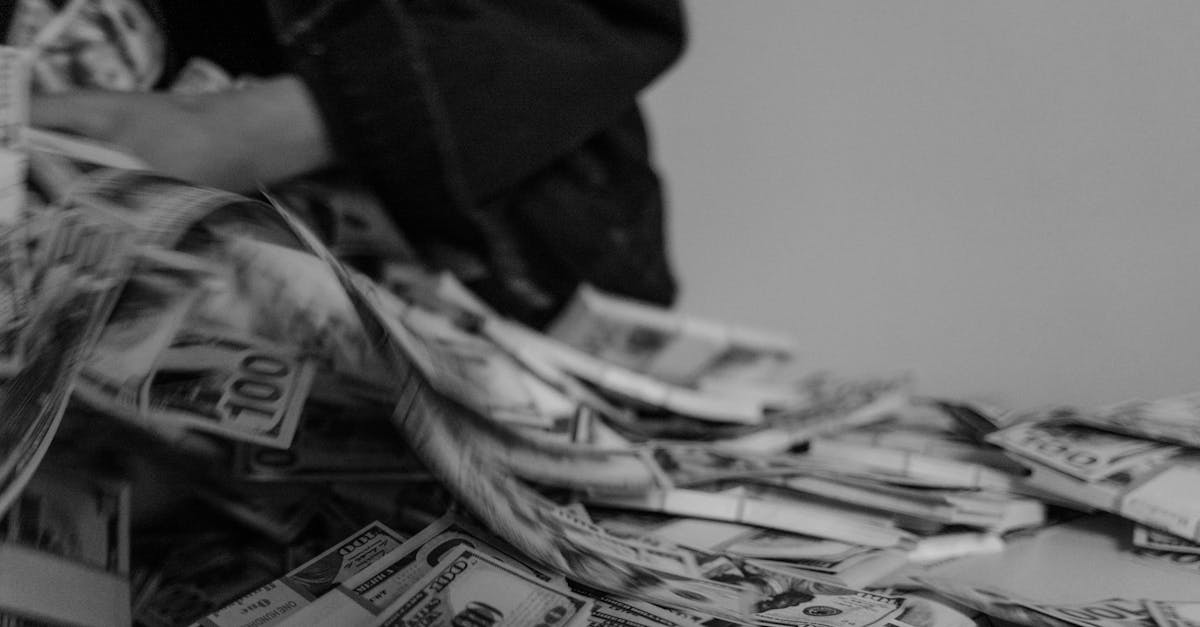 A blur of hands moving through a pile of US dollar bills, captured in black and white.