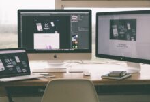 Stylish and efficient workspace with multiple monitors, laptop, and smartphone, showcasing a web design project.