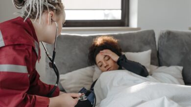 A paramedic examines a sick woman with a stethoscope indoors, providing medical care.