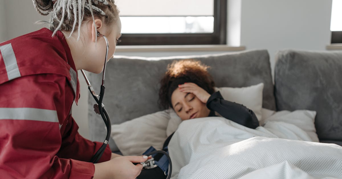 A paramedic examines a sick woman with a stethoscope indoors, providing medical care.