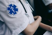 Paramedics in uniform work with medical charts inside an ambulance.