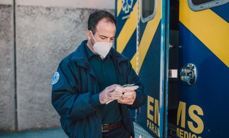 Como Viajar e Trabalhar em Parques Nacionais pelo Mundo - Web Nômade Digital Paramedic in mask working next to EMS vehicle, preparing for emergency response.
