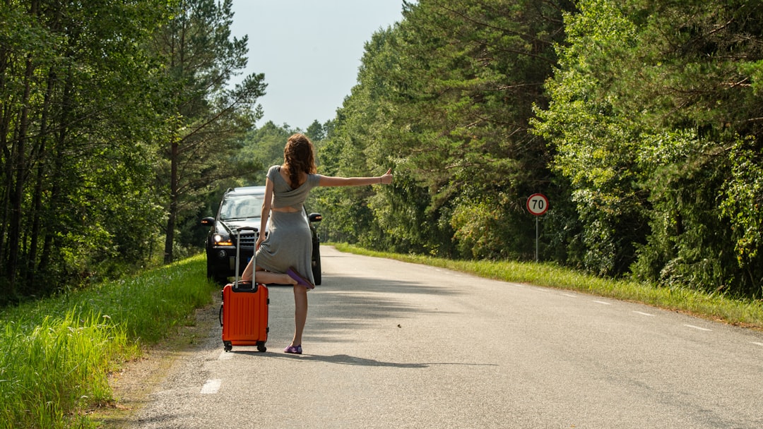 Woman hitchhiking with suitcase on roadside