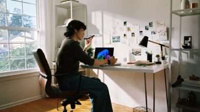 Woman working at desk with laptop and phone.