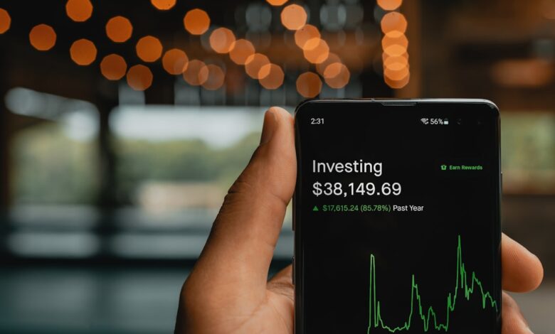 Como Investir em ETFs: Guia para Nômades Digitais - Web Nômade Digital a person holding up a cell phone with a stock chart on it