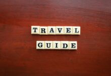 the word travel guide spelled with scrabble tiles