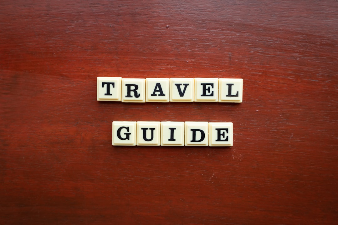 the word travel guide spelled with scrabble tiles