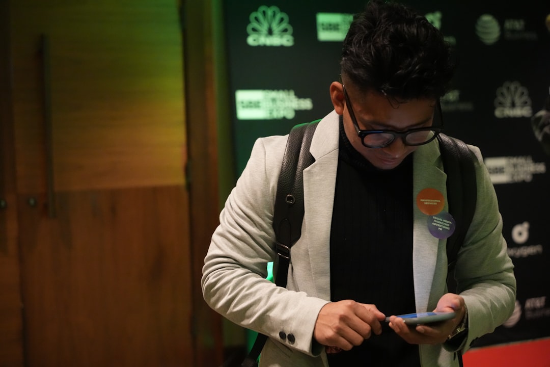 Como Aproveitar o Networking em Eventos para Nômades Digitais - Web Nômade Digital a man wearing glasses looking at his cell phone