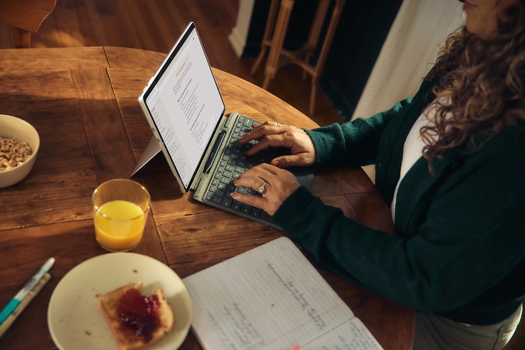 Os Melhores Apps de Produtividade para Nômades Digitais - Web Nômade Digital Woman typing on laptop at wooden table with breakfast.