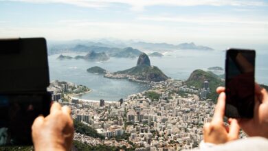 two person holding tablet computer and smartphone in elevated place with the view of city during daytime