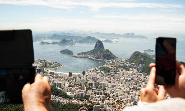 two person holding tablet computer and smartphone in elevated place with the view of city during daytime