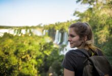 a woman with a backpack looking at a waterfall