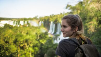 a woman with a backpack looking at a waterfall