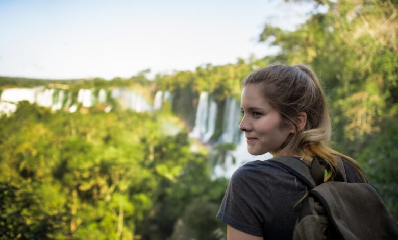 a woman with a backpack looking at a waterfall