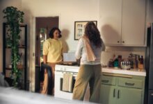 Two women talking in a kitchen while cooking