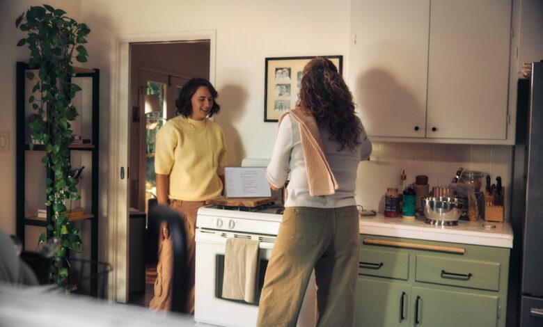 Two women talking in a kitchen while cooking