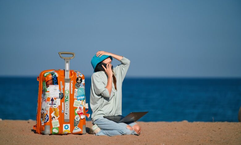 a person sitting on a beach with a suitcase and a laptop