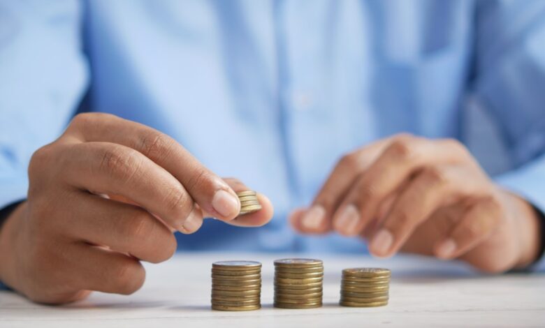 Como Construir uma Renda Passiva com ETFs para Nômades Digitais - Web Nômade Digital a person stacking coins on top of a table