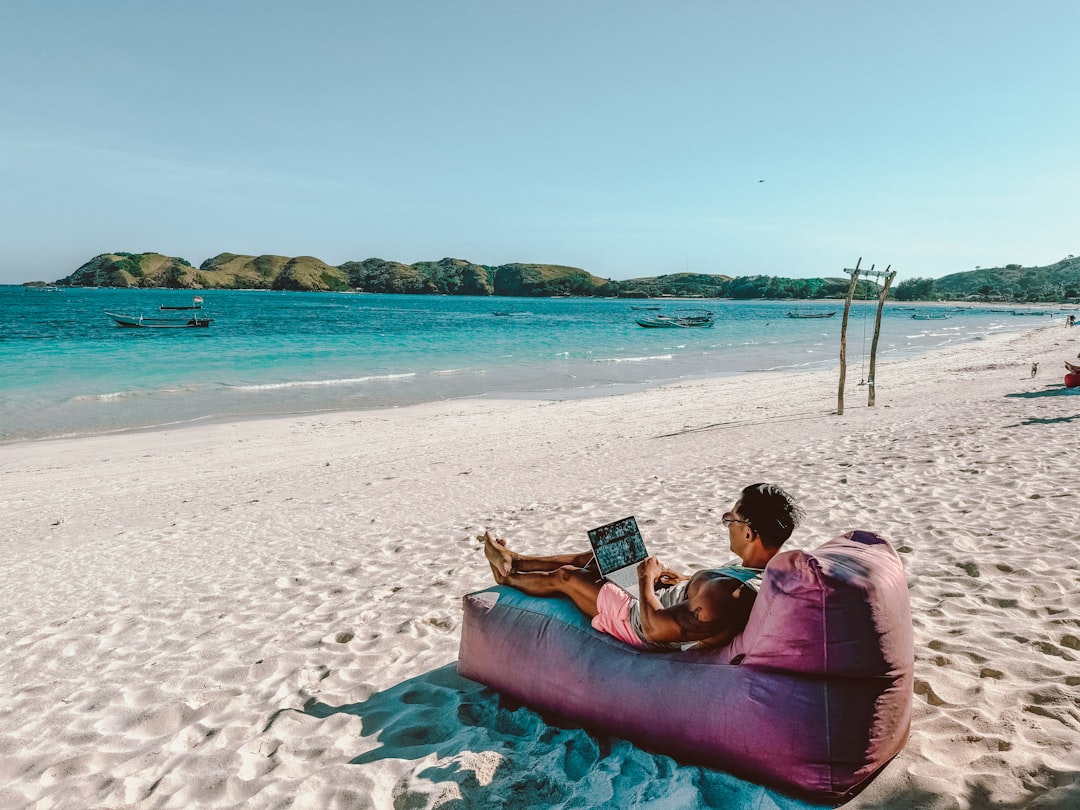 Como Escolher o Melhor Cartão de Crédito para Nômades Digitais - Web Nômade Digital a man sitting on a bean bag on the beach