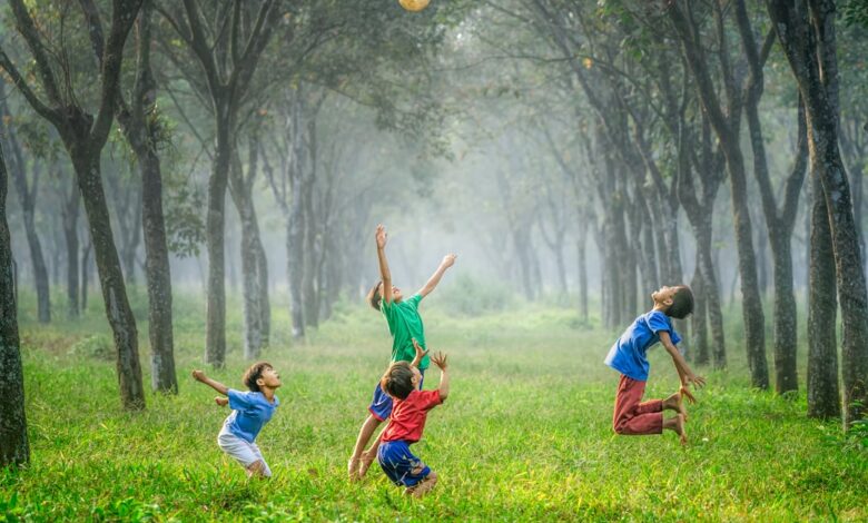 four boy playing ball on green grass