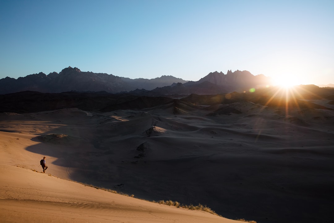 5 Dicas para Manter o Equilíbrio entre Trabalho e Viagem - Web Nômade Digital a person is walking in the desert at sunset