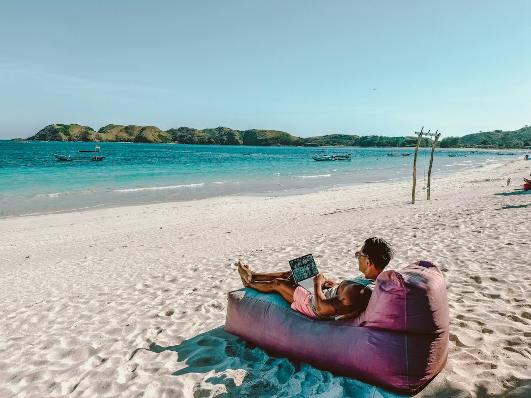Os 5 Melhores Destinos para Nômades Digitais em 2025 - Web Nômade Digital a man sitting on a bean bag on the beach