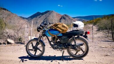 a motorcycle parked on a dirt road with mountains in the background
