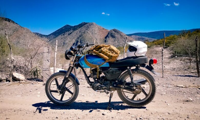 10 Dicas para Viajar com Segurança como Nômade Digital - Web Nômade Digital a motorcycle parked on a dirt road with mountains in the background