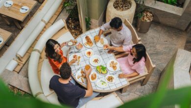 Four people dining at a tiled table with various small plates and drinks
