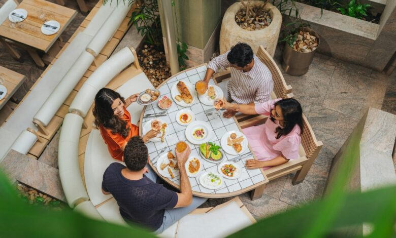 Como Encontrar o Melhor Seguro Viagem para Nômades Digitais - Web Nômade Digital Four people dining at a tiled table with various small plates and drinks