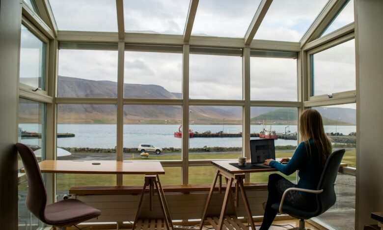 Como Montar um Escritório Remoto em Qualquer Lugar do Mundo - Web Nômade Digital person in blue jacket sitting on brown wooden chair near brown wooden table during daytime