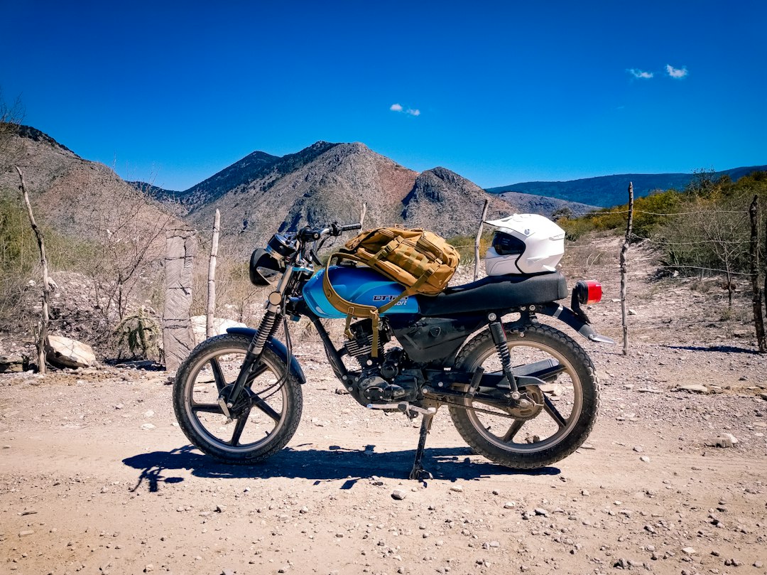 5 Dicas para Viajar com Segurança em Destinos Exóticos - Web Nômade Digital a motorcycle parked on a dirt road with mountains in the background
