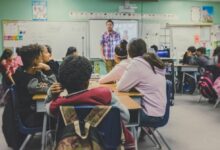 students in classroom with teacher presenting