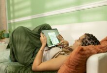 a woman laying on a couch holding a tablet